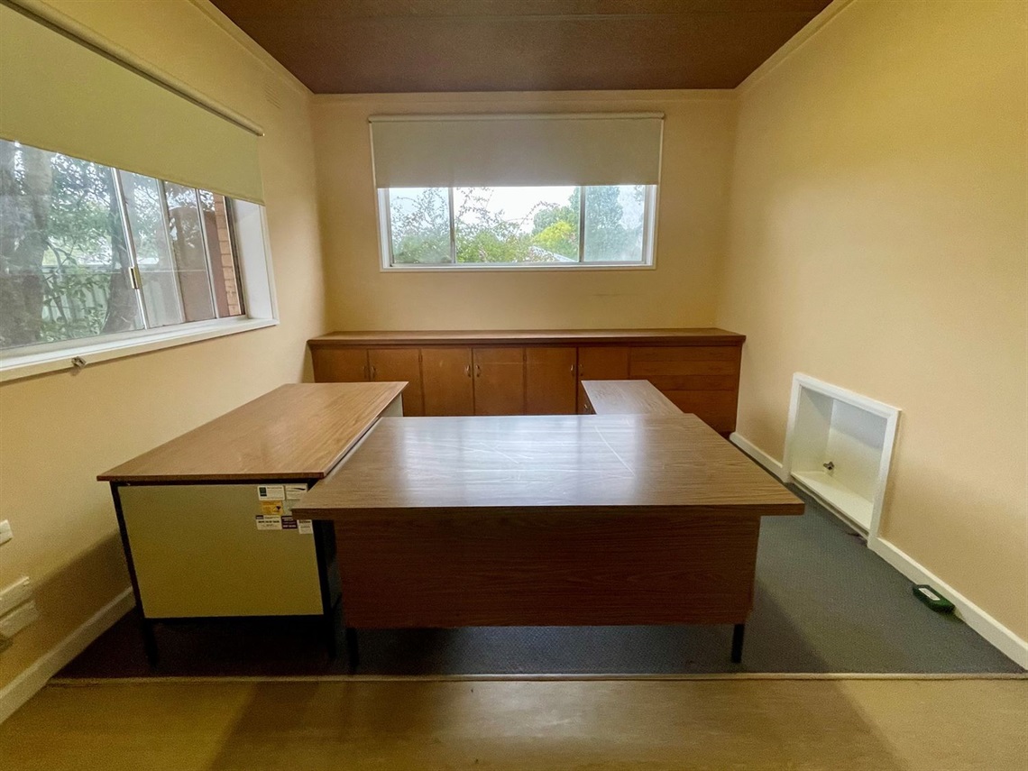 Studio Three at Macarthur Depot showing a workspace with large desk, built-in storage cupboards, and windows overlooking trees.